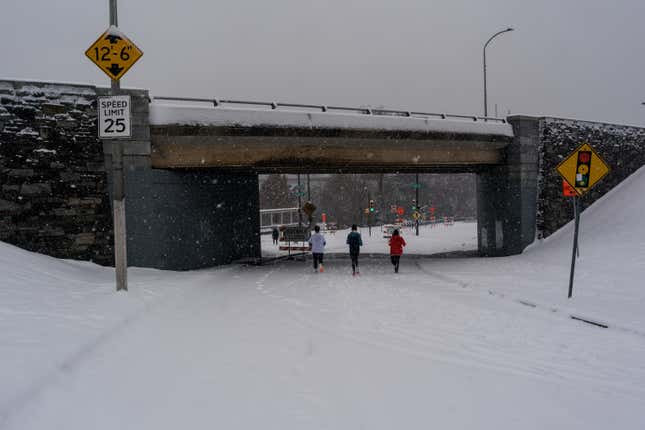 Runners pass under the Spring Garden Street Bridge during snowfall in Philadelphia, United States on January 19, 2024.