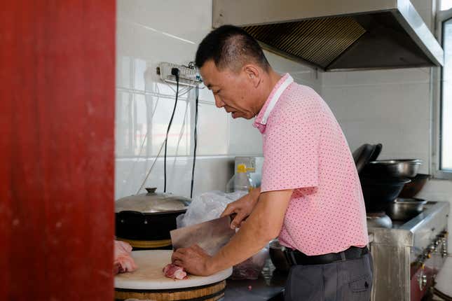 A cook prepares dinner in the kitchen of the main building.