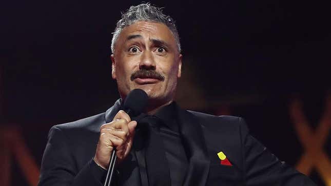 Taika Waititi wearing an all black suit and holding a microphone at the 2020 AACTA Awards in Sydney, Australia late last year.