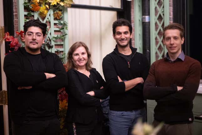 four people standing together with their arms crossed smiling at the camera