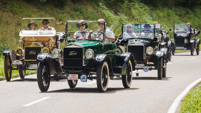 Une photo de six modèles T Ford circulant sur une route. 