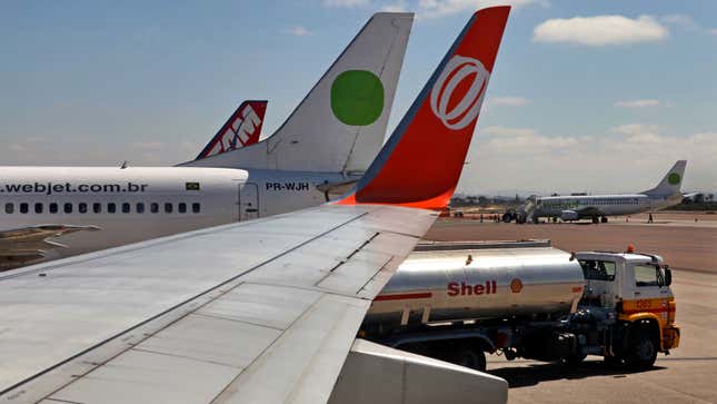 A photo of a Shell tanker next to he wing of a jet plane. 