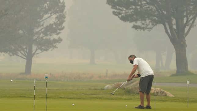 A golfer wears a face mask as he practices his putting at the smoke shrouded Lake Tahoe Golf Course in South Lake Tahoe, California.