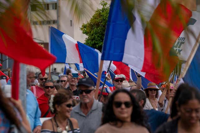 Demonstrators from several loyalist parties wave French national flags  as they march during a demonstration to support the enlargement of the  electorate for the forthcoming provincial elections in New Caledonia, in  Noumea, on April 13, 2024.