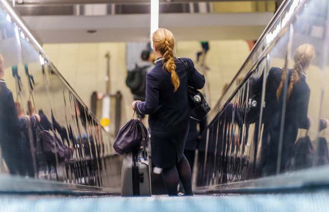  A flight attendant stands with her luggage on the escalator at Rheinmain Airport, Frankfurt Airport