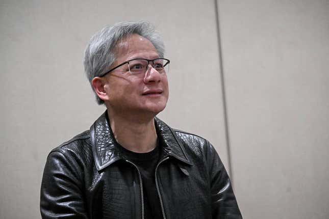 Jensen Huang trägt eine schwarze Lederjacke und eine Brille, blickt nach vorne und lächelt