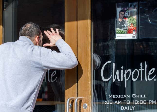 A man looking to eat lunch, looks through the locked front door of the Chipotle in the Washington, DC. community of Georgetown.