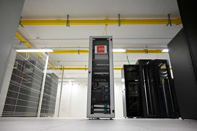 a single computer server in a room with other black structures and yellow pipes on the ceiling