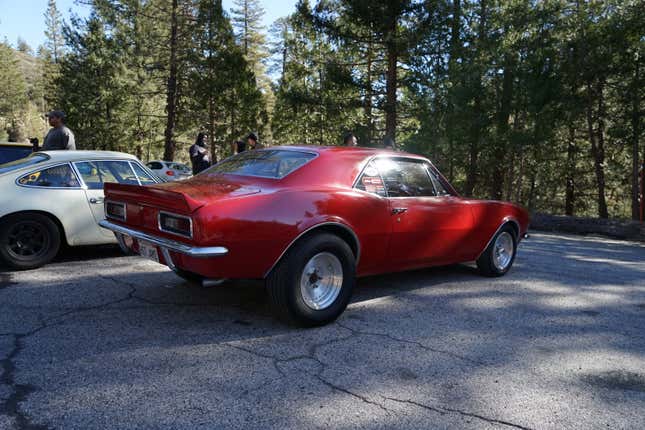 A red modified 1968 Chevy Camaro is parked next to a Porsche 911.