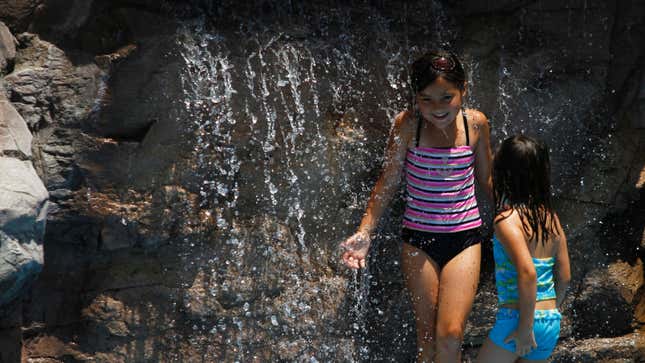 Children keep cool under a waterfall at Tempe Beach Park