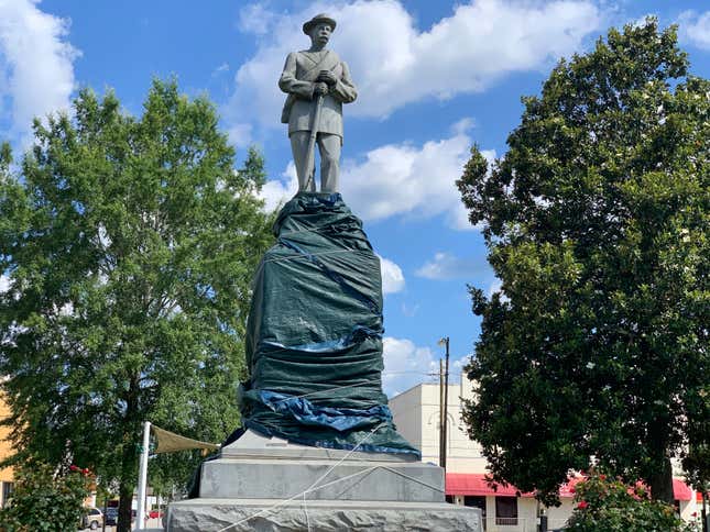 Macon County officials covered the base of a Confederate statue, Friday, June 12, 2020, in Tuskegee, Ala., after it was vandalized with spray-painted obscenities. The Alabama county is seeking to remove the statue that sits in a town square.