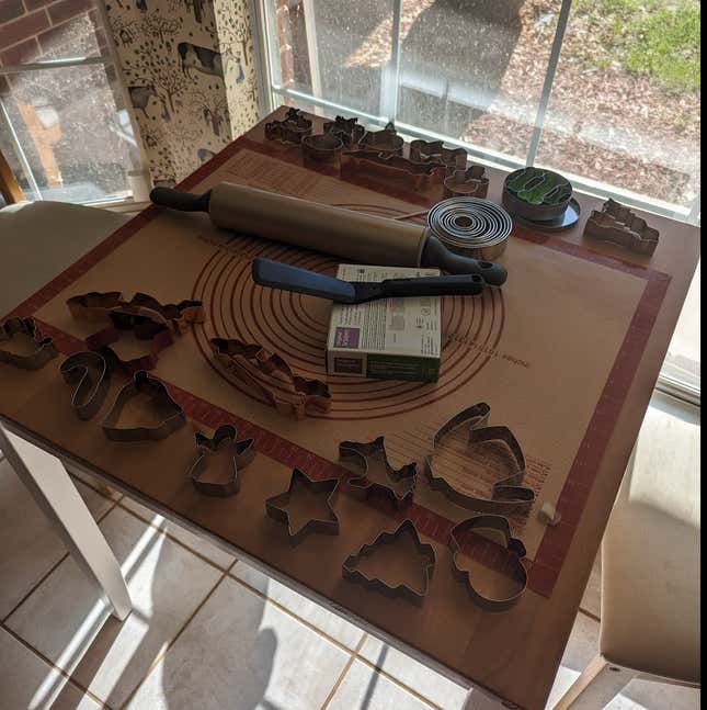 A table set up for crafting that includes race car-shaped cookie cutters, clay, and a silicon mat