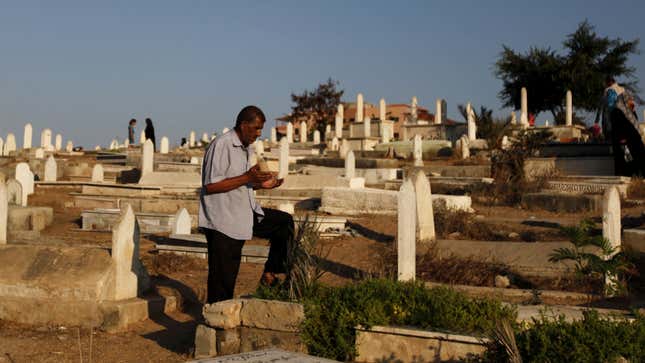 A Palestinian crouches next to a grave in a cemetery as part of the Eid al-Fitr tradition in Gaza.