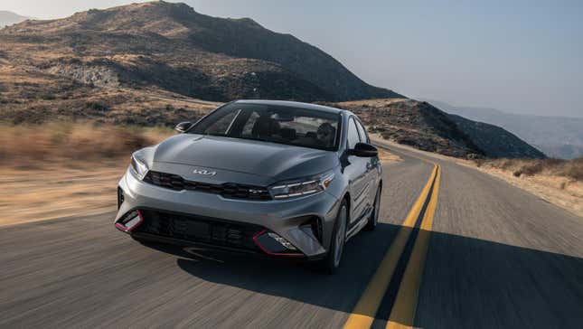 A silver Forte driving on a desert road