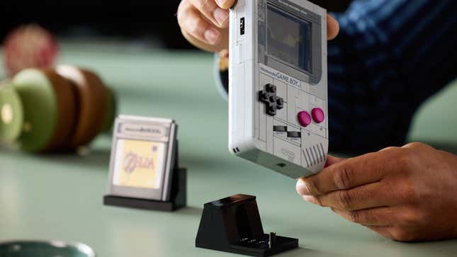 A human is putting the Lego Game Boy onto its stand.