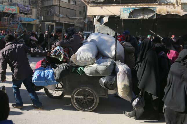 Aleppo residents walk with their belongings as they gather to be evacuated. (Reuters/Abdalrhman Ismail)