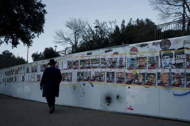 A man looks at photographs on a wall of hostages who were abducted during the Oct. 7, unprecedented Hamas attack on Israel, in Jerusalem, Israel, Tuesday, Jan. 30, 2024. (AP Photo/Leo Correa)