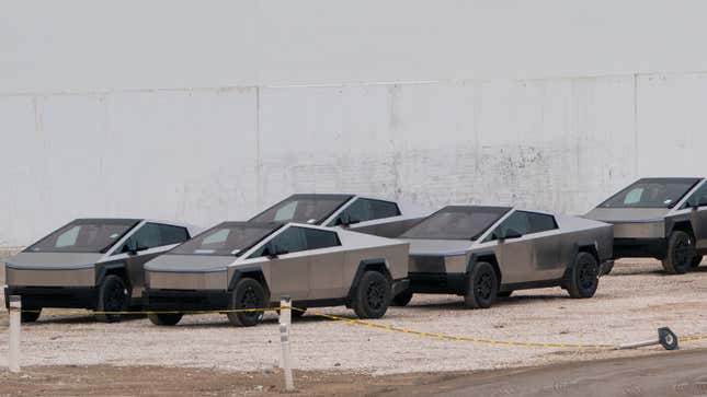 A photo of five Tesla Cybertrucks parked on gravel. 