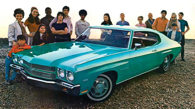 A photo of a group of people standing round a blue Chevrolet Chevelle car. 