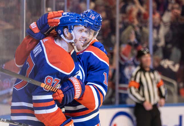 Edmonton Oilers&#39; Connor McDavid (97) celebrates his 100th assist this season with Zach Hyman (18) against the San Jose Sharks during the second period of an NHL hockey game in Edmonton, Alberta, on Monday, April 15, 2024. (Jason Franson/The Canadian Press via AP)