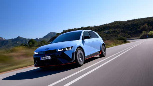 A blue Ioniq 5 N driving on a road in front of mountains 