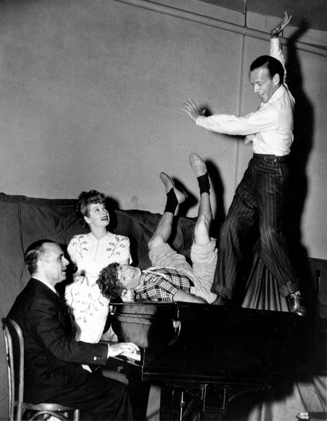 Jose Iturbi, playing the piano, Lucille Ball, Harpo Marx, on piano, and Fred Astaire, dancing on piano, rehearse backstage at the Madison Square Garden in New York City before going on in the Hollywood Bond Cavalcade Show on Sept. 11, 1943.