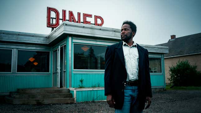 A man stands outside a diner. 