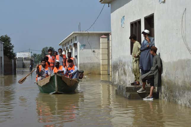 Armed members of Alkhidmat Foundation patrol on a boat at a residential area submerged in floodwater in Nowshera of Khyber Pakhtunkhwa province on August 29, 2022.