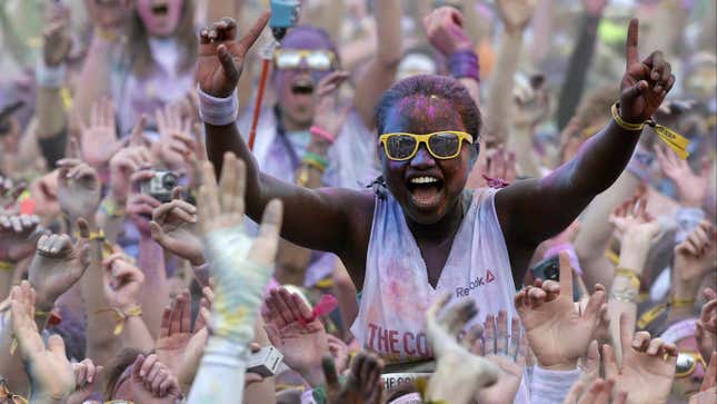 A participant stands on the shoulders of her friends at a Color Run.