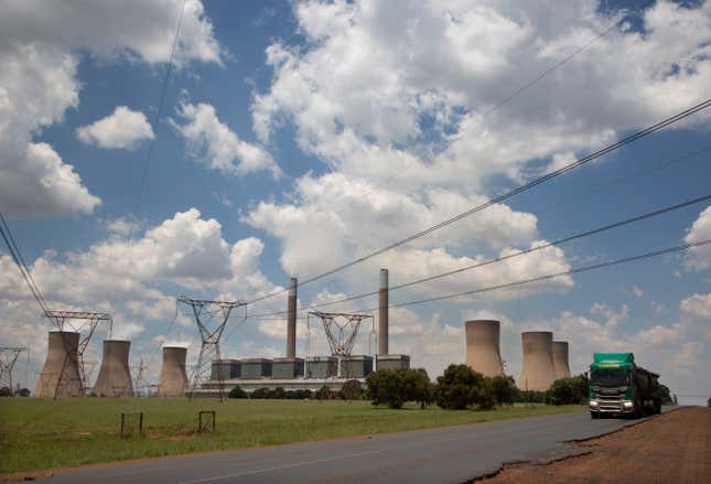 FILE — A coal truck, right, passes the coal-powered Duvha power station, near Emalahleni (formerly Witbank) east of Johannesburg, Thursday, Nov. 17, 2022. The World Bank has approved a $1 billion loan for South Africa to help it address an energy crisis that has peaked this year with the country’s worst electricity blackouts. It has forced South Africa to lean more heavily on its highly polluting coal-fired power stations. (AP Photo/Denis Farrell/File)