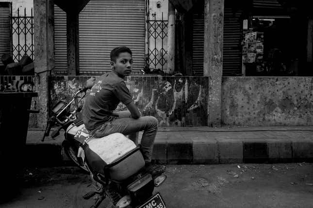 A boy in a rare fragment of stillness on the side of a busy thoroughfare.