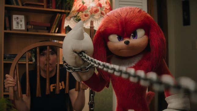Knuckles holds a chain as Wanda cowers behind a broken chair.
