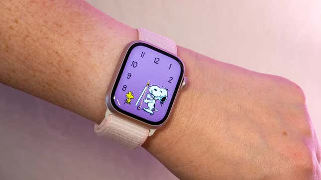 An Apple Watch with a pink finewoven band and a Snoopy watch face.