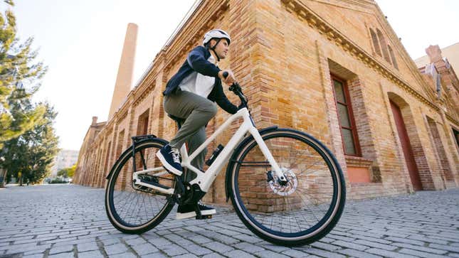 A photo of a person riding an Orbea bike on a cobbled street. 