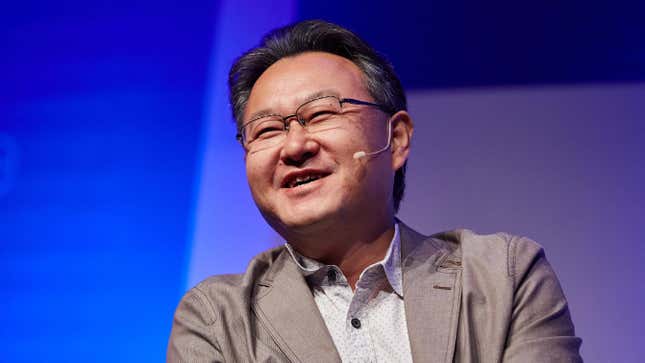 Shuhei Yoshida speaks on stage at a gaming event. 