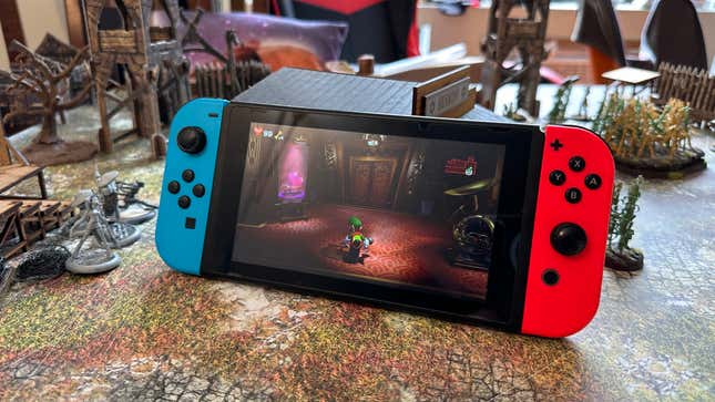 A Nintendo Switch playing the game Luigi's Mansion 3 on a table with several miniature scenery
