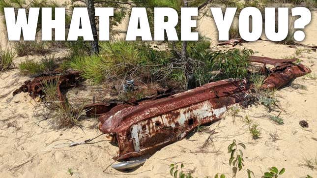 Image for article titled This Beach-Buried Wrecked Car Is Defying Identification And It&#39;s Driving Me Bonkers