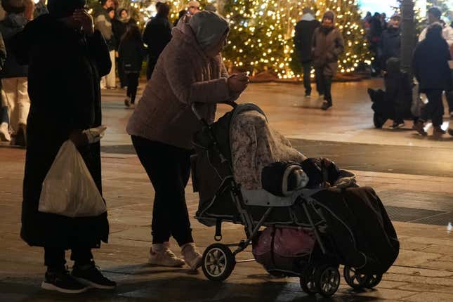 Migrants wait on the City Hall plaza in Paris, Monday Dec.25, 2023 as migrant families meet on Christmas Day seeking somewhere to stay. About 50 families with children between three months and 10 years old gathered on City Hall plaza on Christmas evening, to meet members of aid groups who distribute food, blankets and diapers and help find temporary lodging. (AP Photo/Nicolas Garriga)