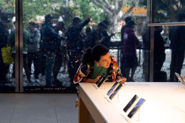 File - As shoppers wait in the background, a woman looks at Apple&#39;s new iPhone 15 at an Apple Store in Los Angeles, Friday, Sept. 22, 2023. On Friday, the Commerce Department issues its August report on consumer spending. (AP Photo/Jae C. Hong, File)