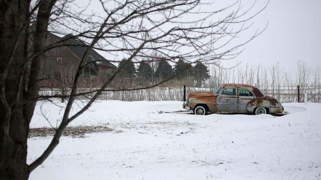 A rusty car in a snowy field 