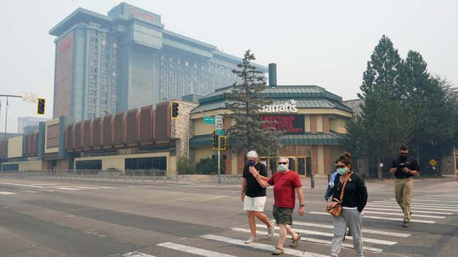 Harrah's Lake Tahoe Casino is shrouded in smoke as face mask wearing pedestrians cross the street at the California-Nevada line.