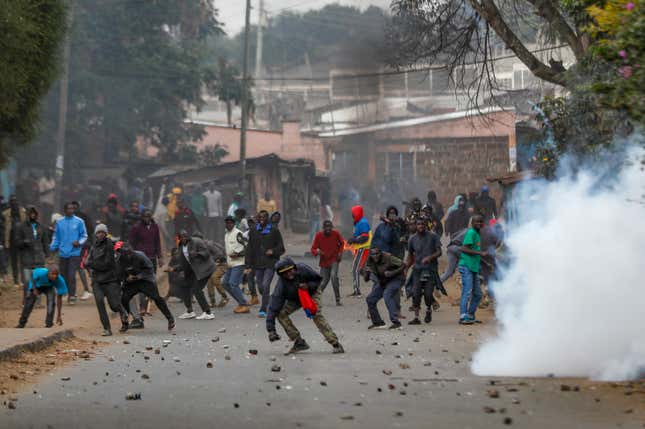 FILE - Protesters throw rocks at police during clashes next to a cloud of teargas in the Kibera area of Nairobi, Kenya on July 19, 2023. The Kenyan High Court on Tuesday Nov. 28, 2023 struck out key clauses of a controversial finance law that has been blamed for significantly raising taxes and the cost of living in East Africa’s largest economy. (AP Photo/Brian Inganga, File)