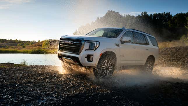 A white GMC Yukon splashing through standing water