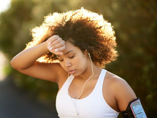 Black jogger woman wiping sweat off brow