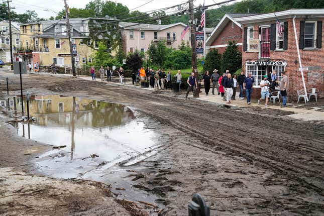 FILE - New York Gov. Kathy Hochul and a group of emergency workers and journalists pass along Main Street, July 10, 2023, in Highland Falls, N.Y., following heavy rain. New York Gov. Kathy Hochul has signed a bill Friday, Sept. 22, 2023, requiring people selling their homes to disclose whether their properties have been flooded or are at risk for future flooding. (AP Photo/John Minchillo, File)