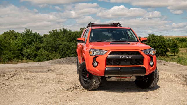 A photo of a red Toyota 4Runner SUV parked on dirt. 