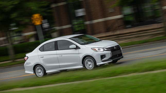 A white Mitsubishi Mirage G4 driving on a road in front of grass