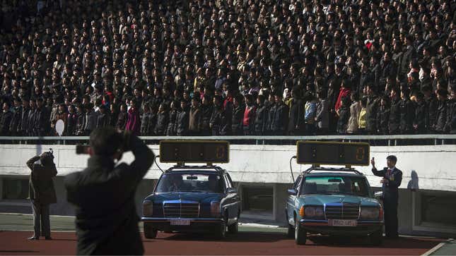 Cars with timing clocks wait for the start of a marathon to begin at Kim Il Sung Stadium.