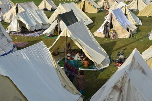 Displaced people sit in their tents at a makeshift camp after fleeing from their flood-hit homes following heavy monsoon rains in Charsadda district of Khyber Pakhtunkhwa on August 29, 2022.
