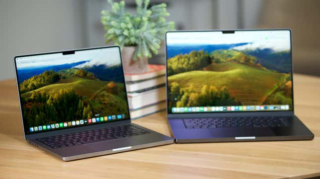 A 14-inch MacBook Pro with M3 in silver next to a 16-inch MacBook Pro with M3 Max in front of a stack of books and a plant.